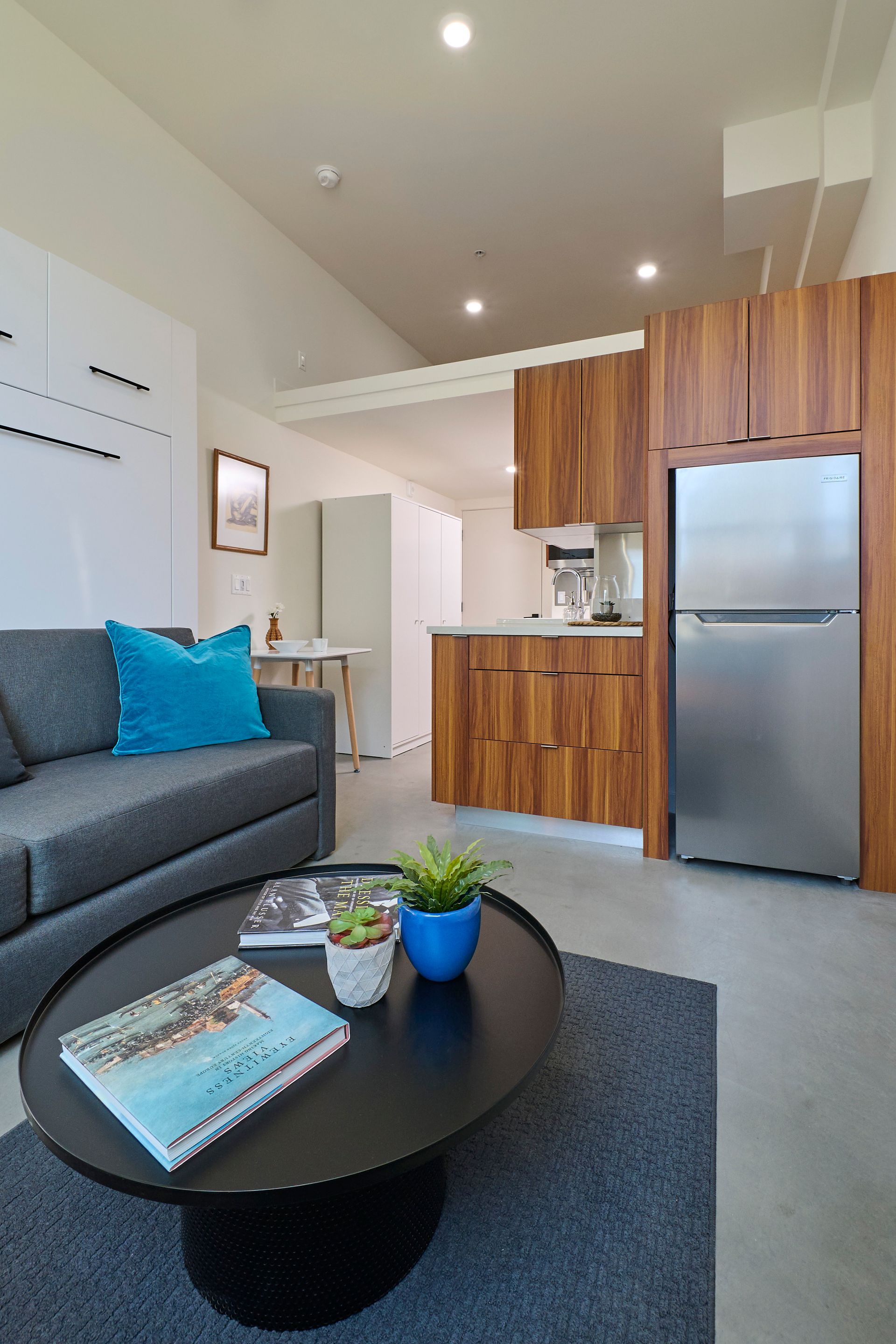 A living room with a couch , coffee table , and refrigerator.