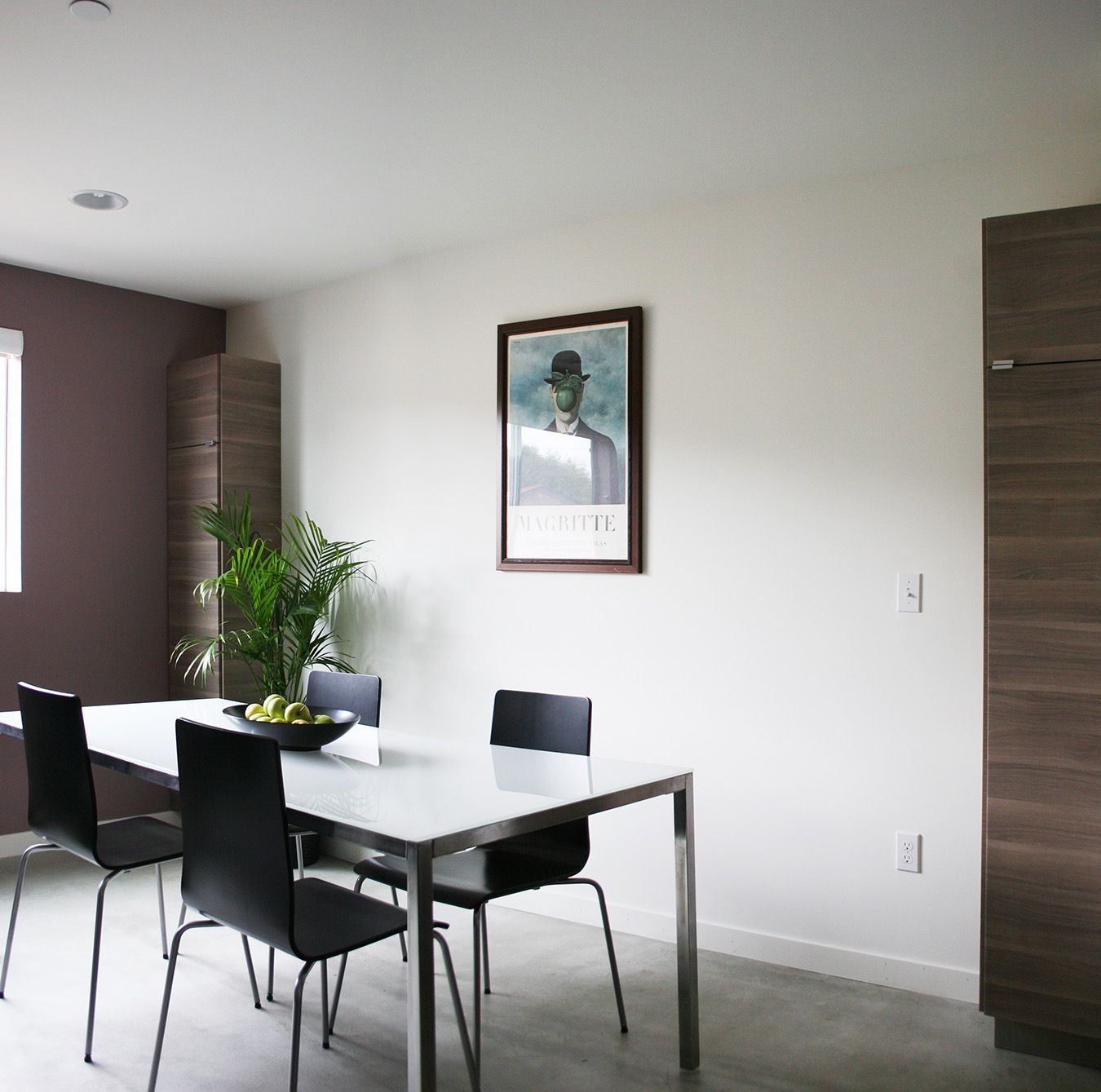 A dining room with a table and chairs and a picture on the wall
