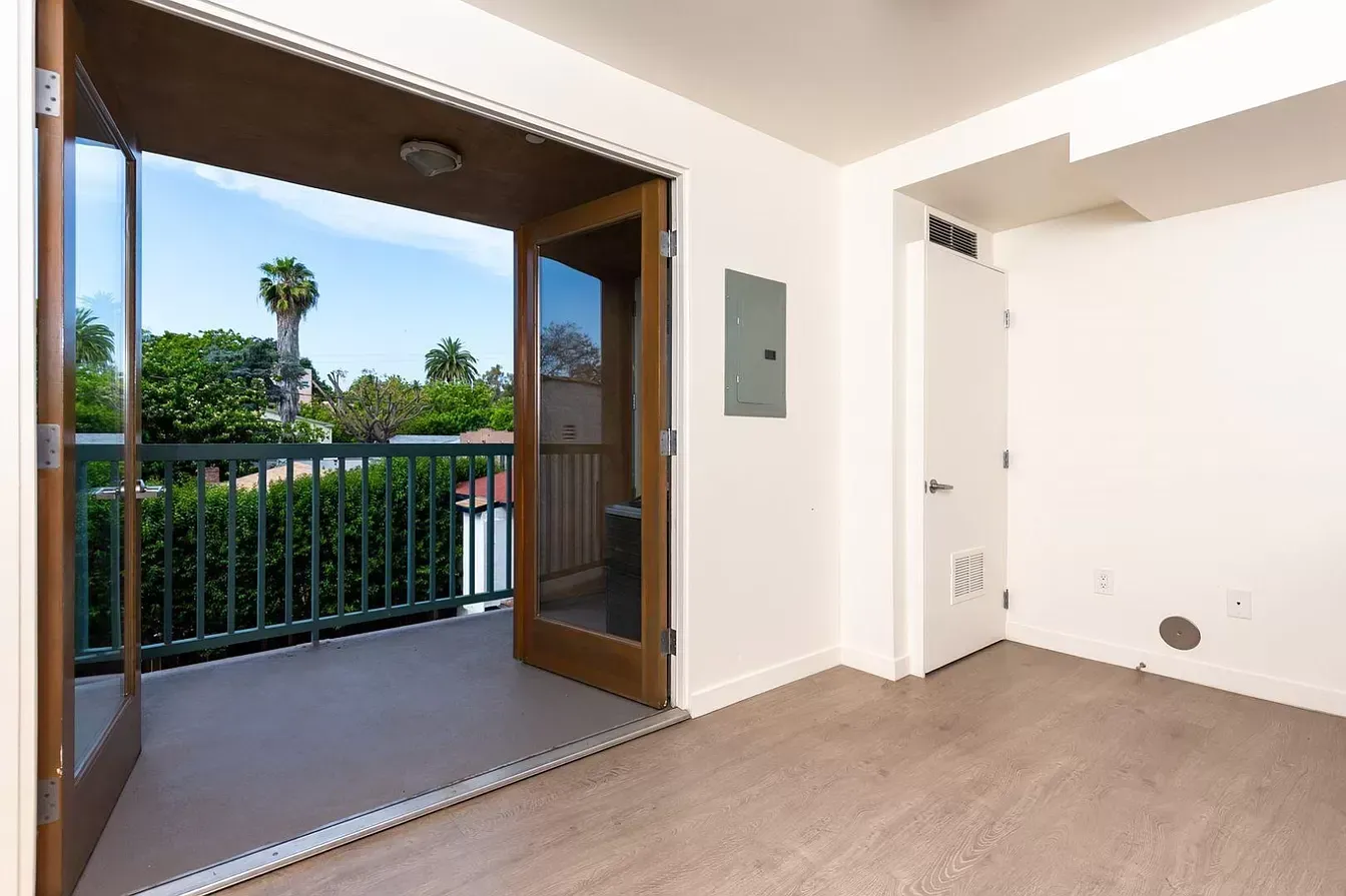 An empty room with a balcony and sliding glass doors