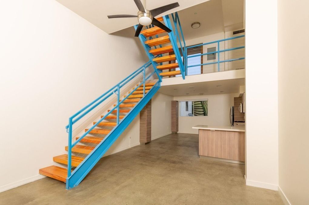 An empty room with a blue staircase and a ceiling fan