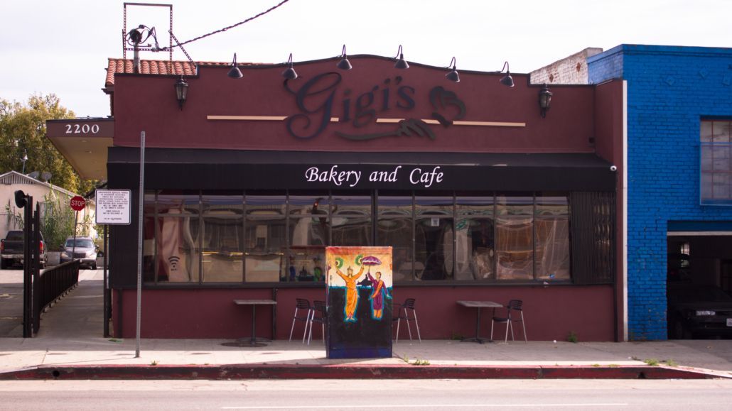 Street view of a red café storefront with large windows and colorful street art on the sidewalk.