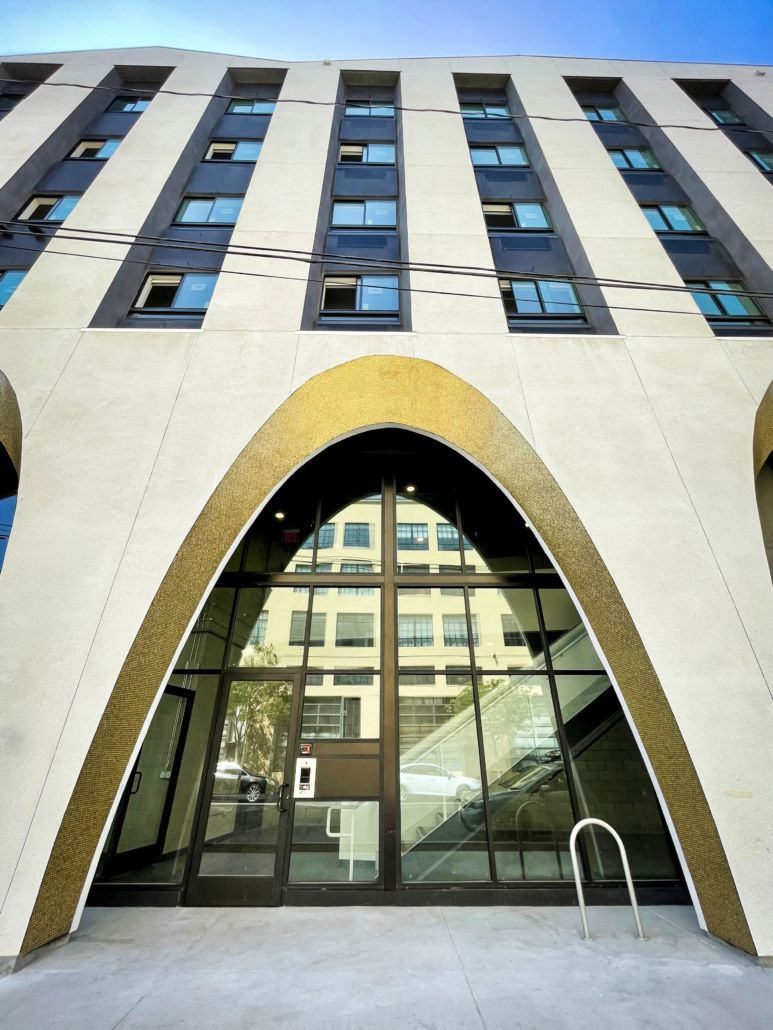 Modern building entrance with a tall arched doorway and reflective glass windows