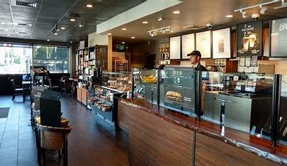 Interior of a Starbucks: a counter with pastries, a barista, and menu boards.