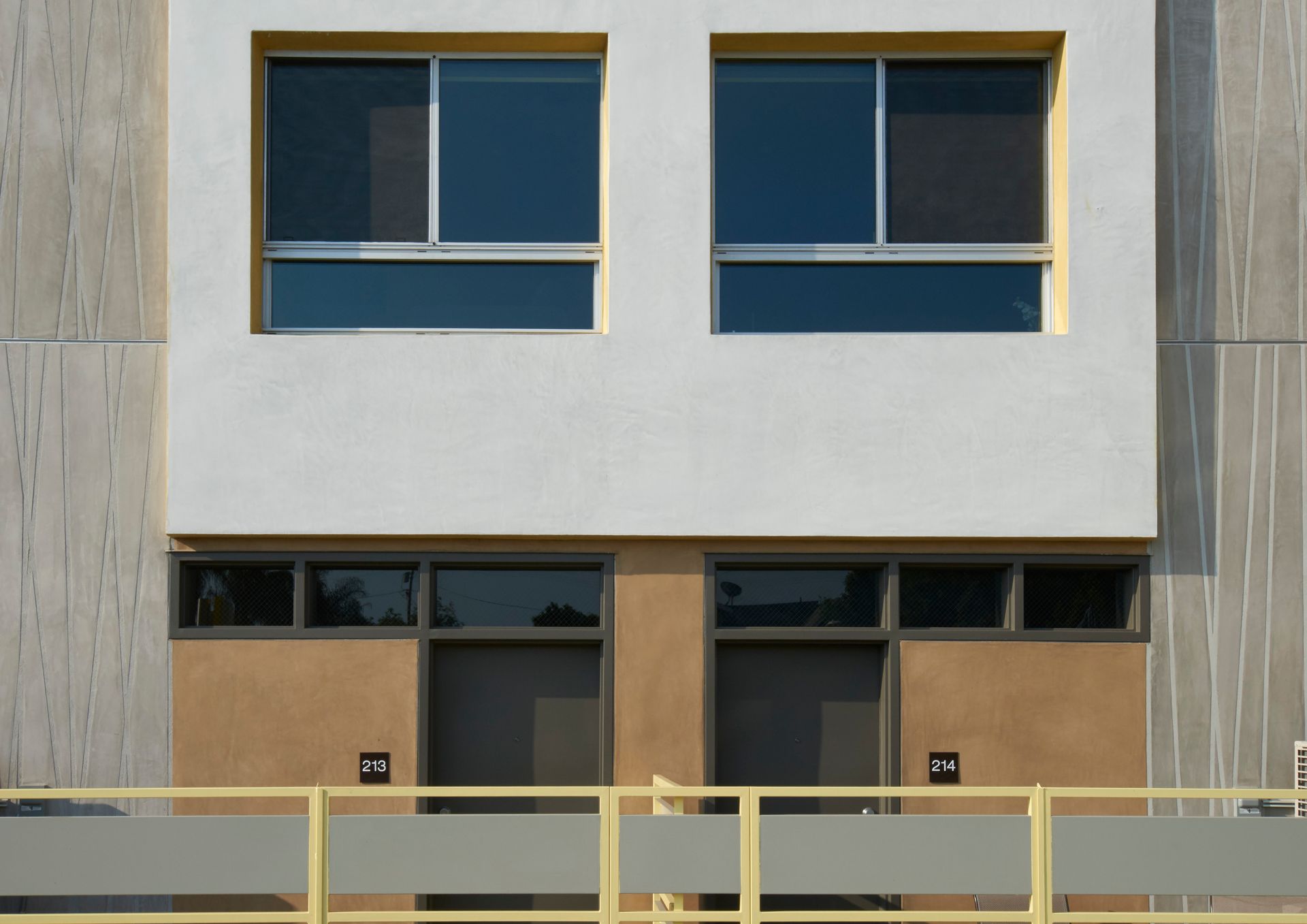 The front of a building with two windows and a yellow railing.