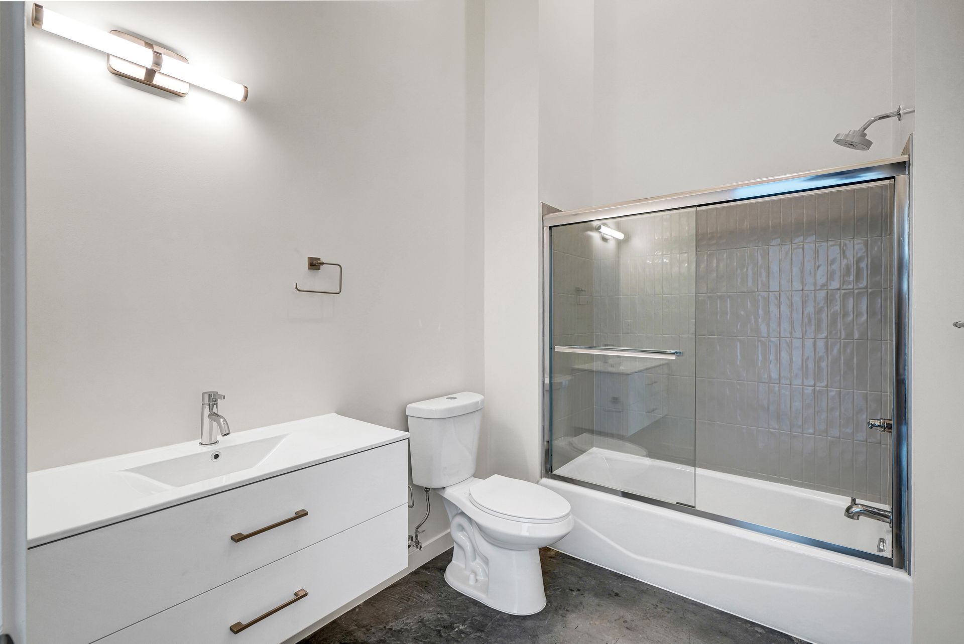 White bathroom with a sink, toilet, and a glass-enclosed shower/tub.