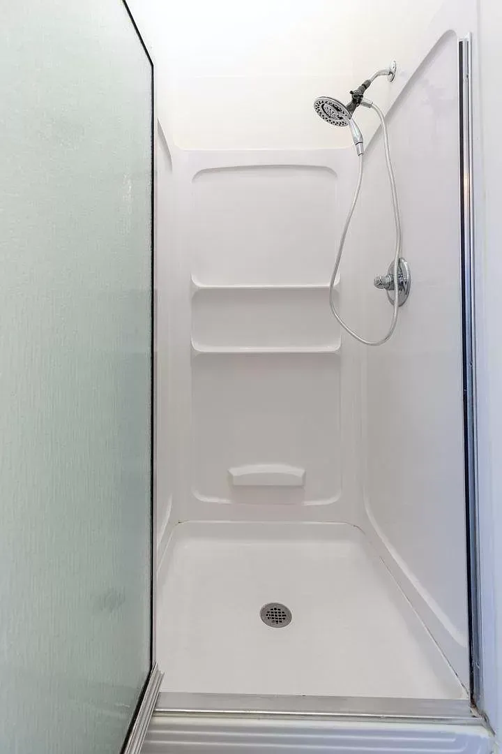 A shower stall with a shower head and shelves in a bathroom.