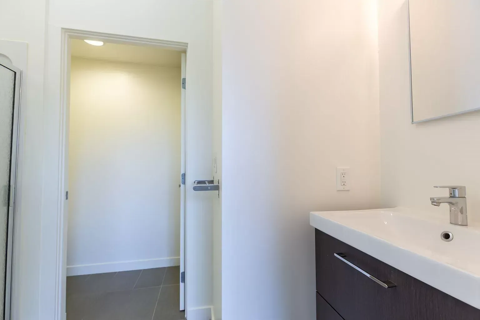 A bathroom with a sink , mirror and door.