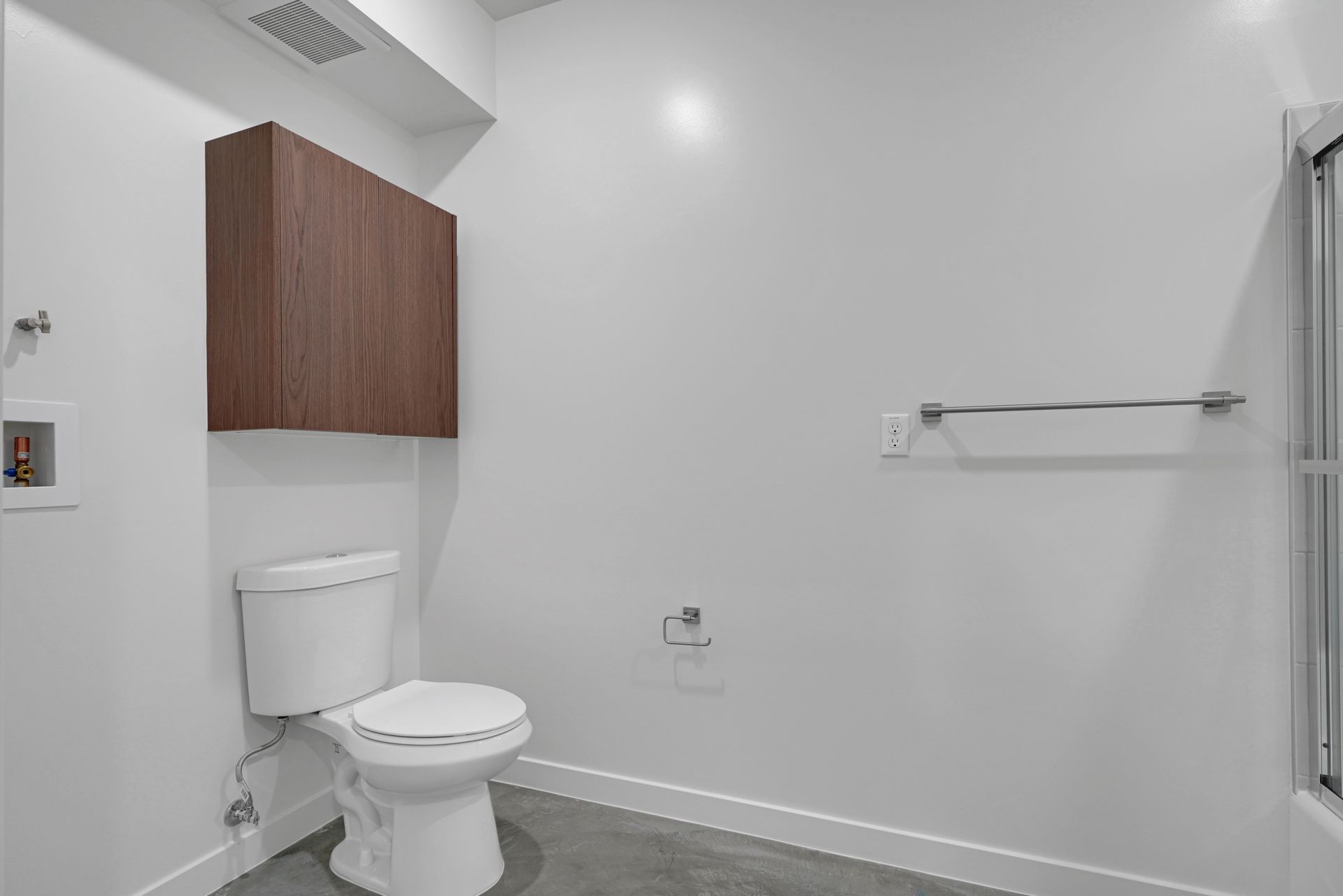 Modern bathroom with a white toilet, brown cabinet, and a towel rack.