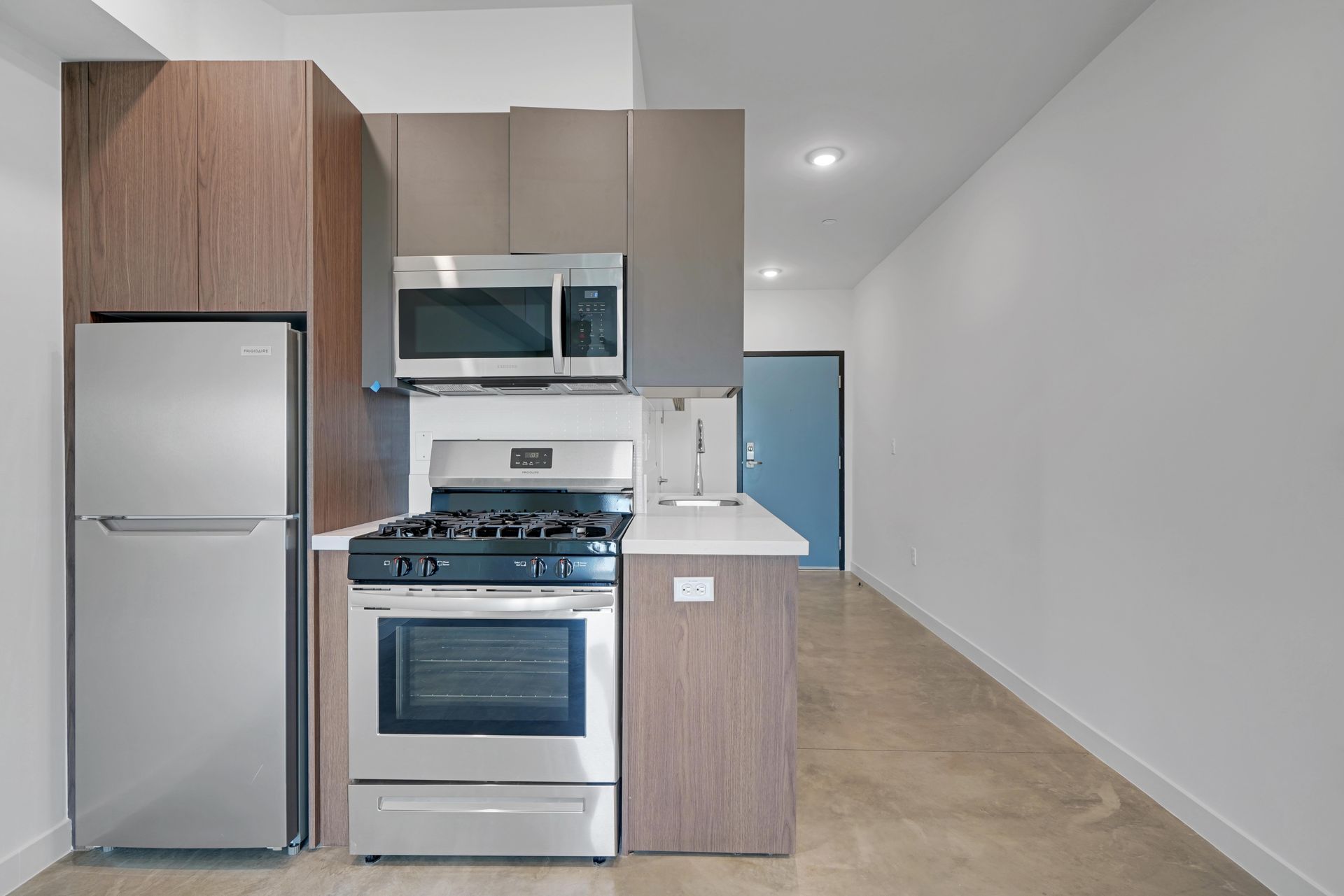 Modern kitchen with stainless steel appliances, brown cabinets, and a white countertop.