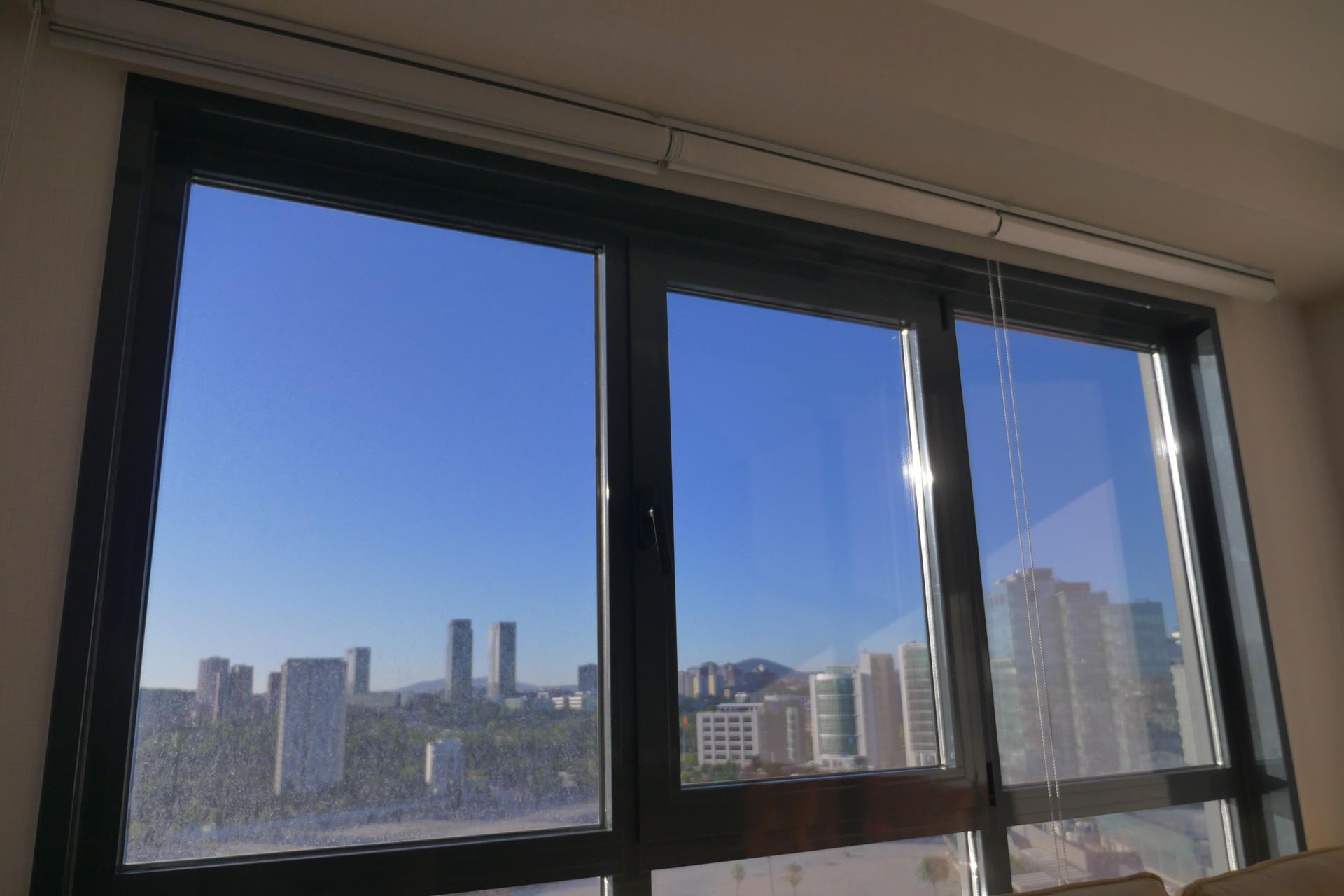 Large window overlooking city skyline and bright blue sky.