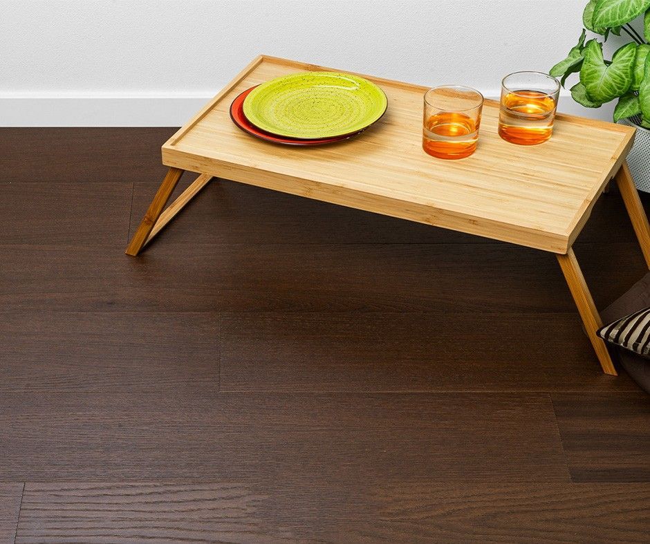Vassoio di legno con cibo e bevande su pavimento di legno scuro.