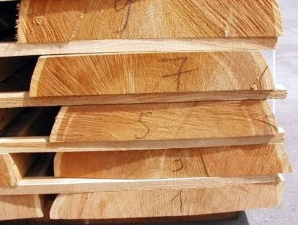 Primo piano di assi di legno impilate e numerate, con venature visibili.