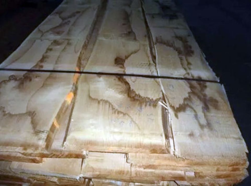 Pila di assi di legno chiaro legate insieme con cinghie scure.