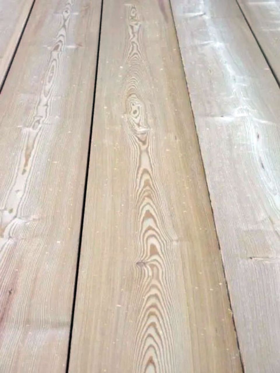 Tavole di legno di colore beige chiaro con venature del legno visibili.