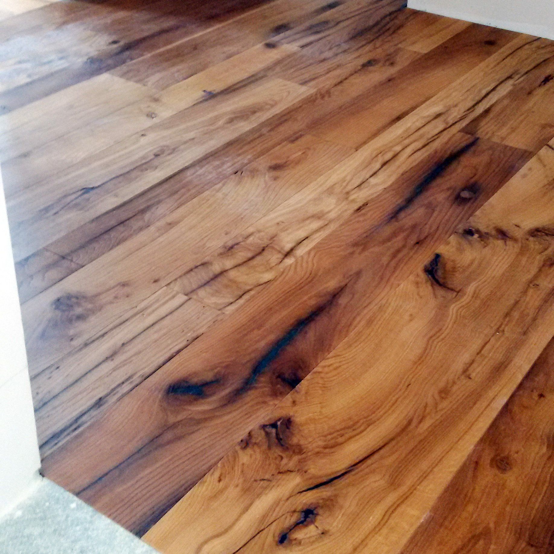Primo piano delle assi del pavimento in legno con intense tonalità marroni e venature del legno visibili.