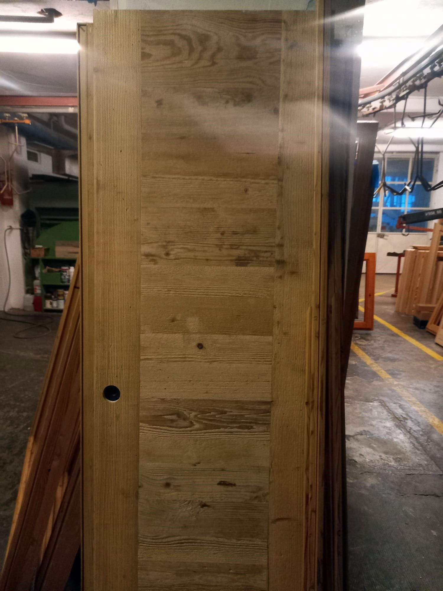 Porta in legno, marrone chiaro con assi orizzontali, in un ambiente da laboratorio.