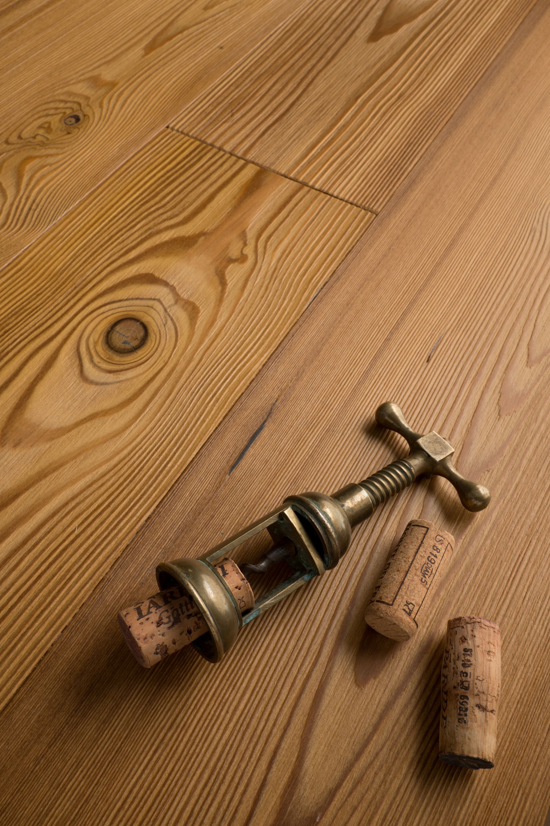Cavatappi con tappi di sughero su un pavimento in legno marrone chiaro con venature del legno.