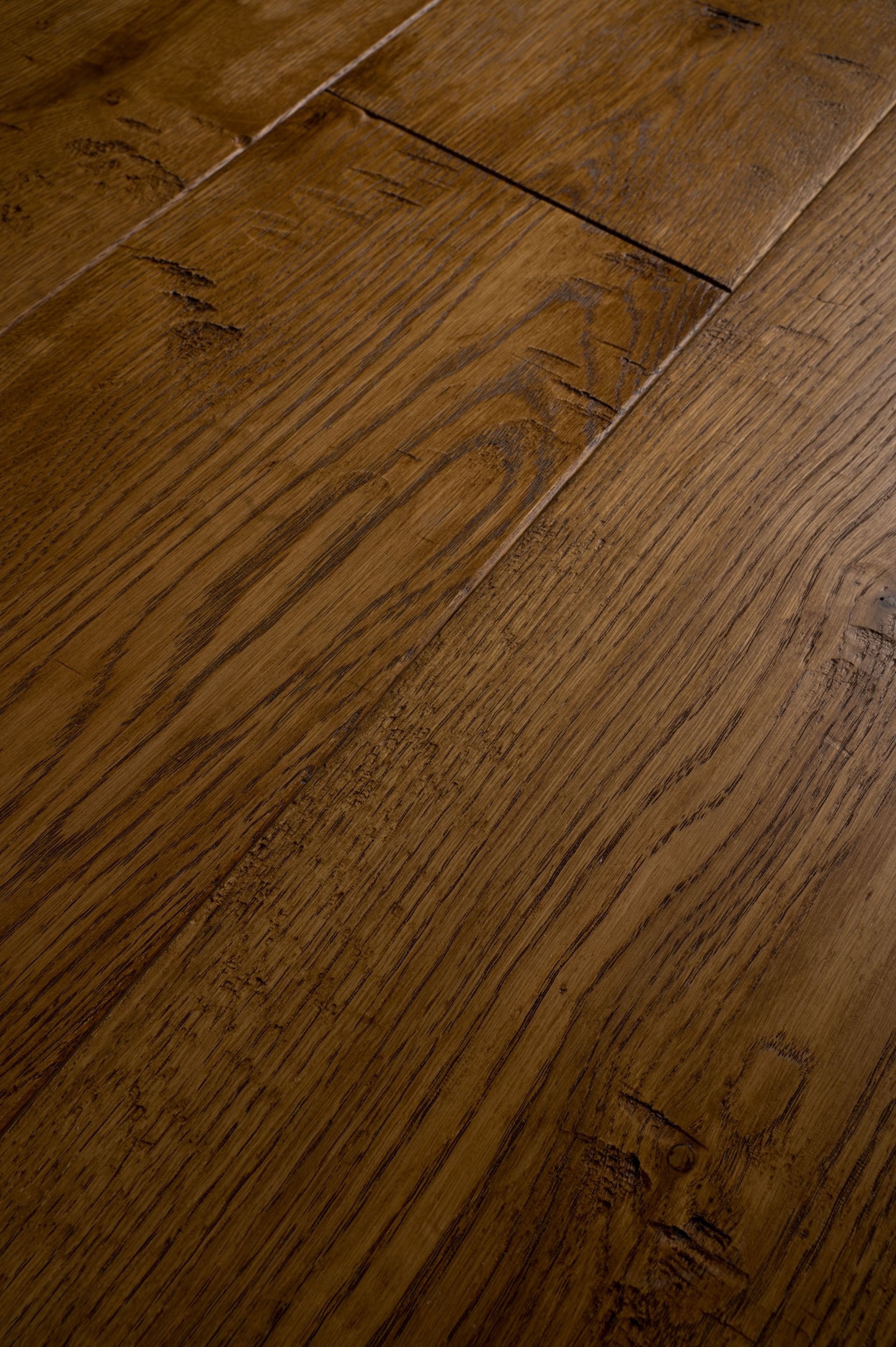 Primo piano del pavimento in legno marrone, che mostra le venature del legno e la consistenza della superficie.