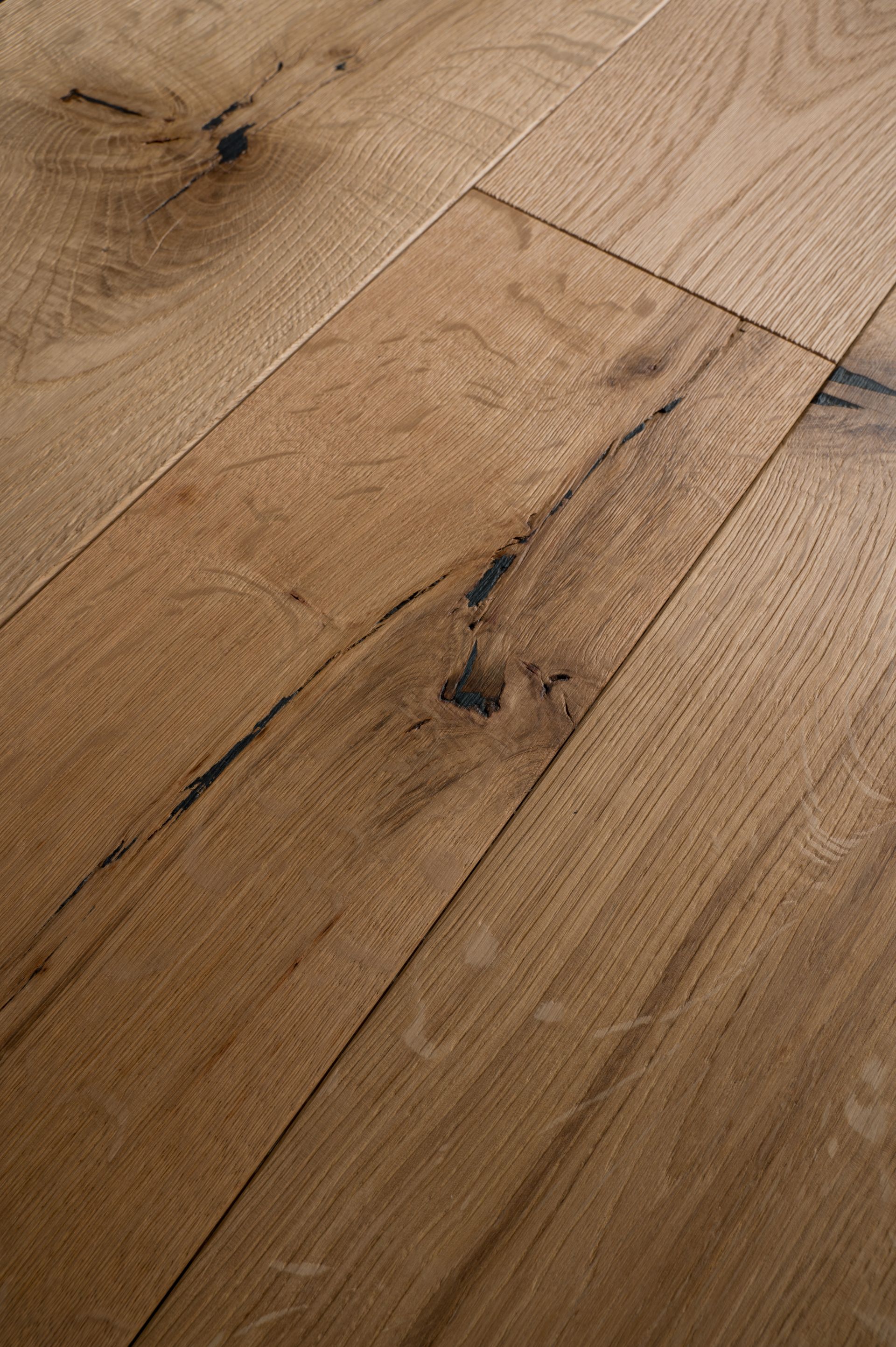 Pavimento in legno con diverse tonalità di marrone e scuro, nodi irregolari. 