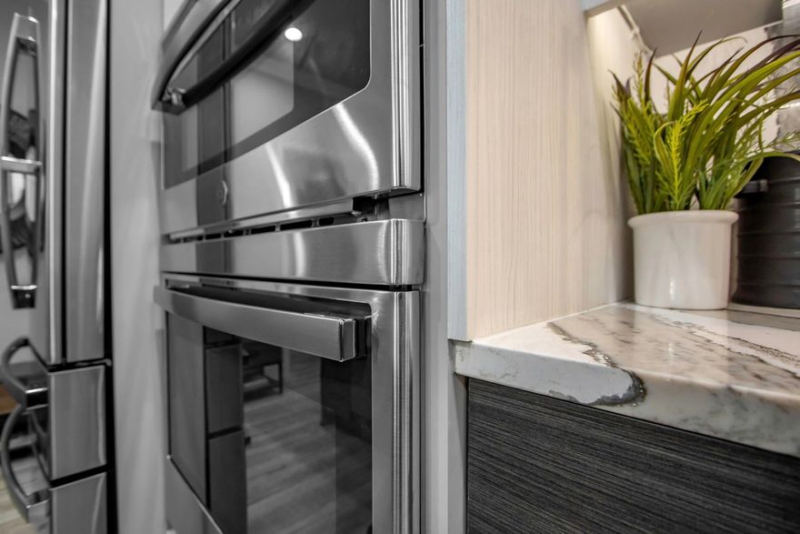 Modern built-in kitchen with stainless steel ovens, cupboards, and a cooking scene on the left