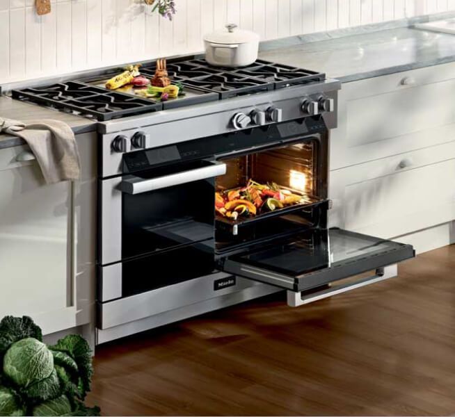 Modern built-in kitchen with stainless steel ovens, cupboards, and a cooking scene on the left
