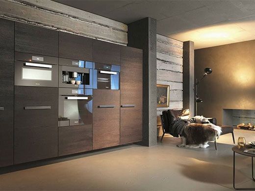 Modern living room with dark wood wall unit, built-in TV, and seating area under warm lighting