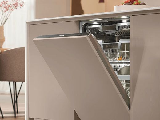 Open dishwasher in a modern kitchen with loaded racks and a taupe front panel