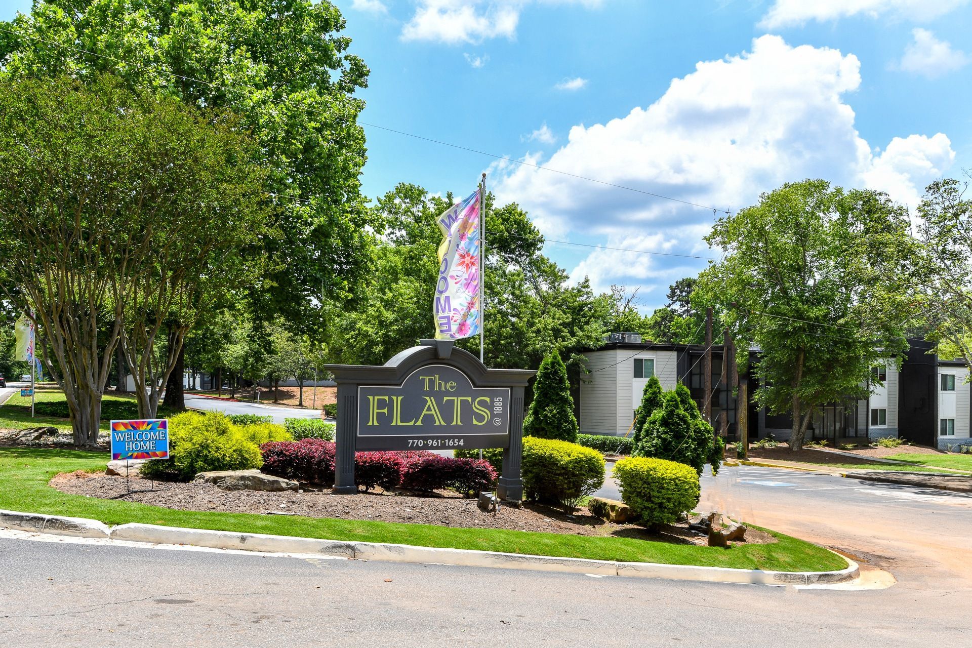 a sign that says the flats in front of trees and bushes