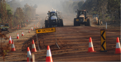 A Group Of Tractors Are Driving Down A Dirt Road — PTS Traffic Management in Smithfield, QLD