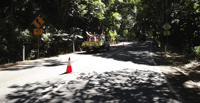 A Yellow Truck Is Driving Down A Road Next To A Red Cone — PTS Traffic Management in Smithfield, QLD