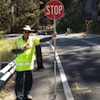 A Man Is Standing Next To A Stop Sign On The Side Of The Road — PTS Traffic Management in Smithfield, QLD