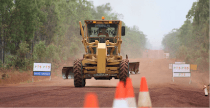A Bulldozer Is Driving Down A Dirt Road — PTS Traffic Management in Smithfield, QLD