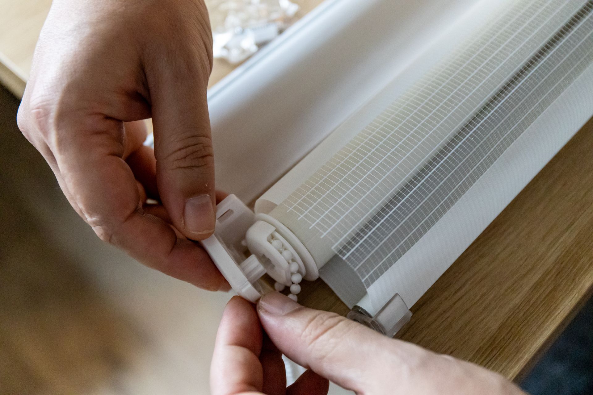 Hands attaching a white fixture to a ribbed light cover on a wooden table
