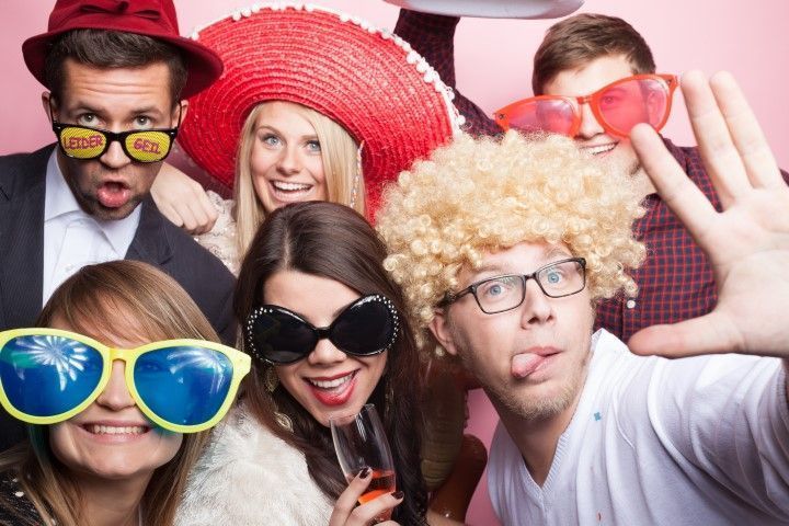 Group of people wearing colorful novelty glasses and wigs posing for a playful selfie
