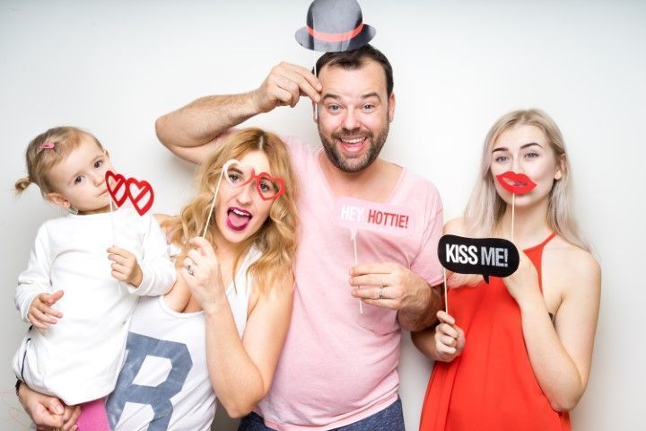 Four people posing playfully with Valentine signs and red lipstick marks against a white background
