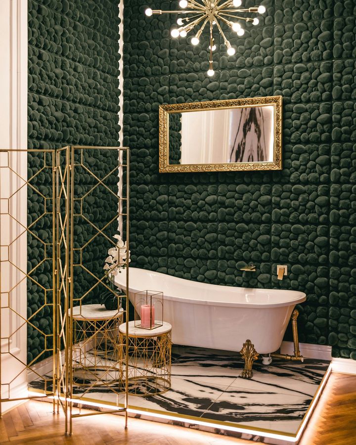 Elegant bathroom with dark green quilted walls, gold accents, chandelier, freestanding tub, and marble floor