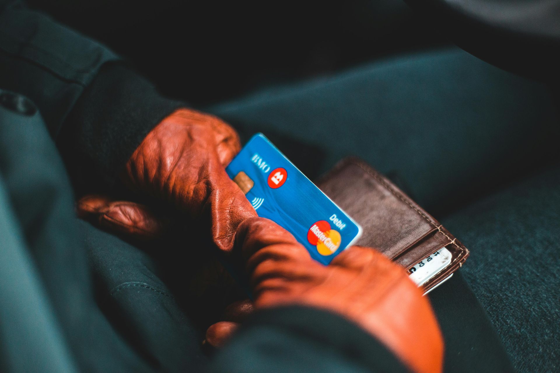 A person is holding a credit card and a wallet.
