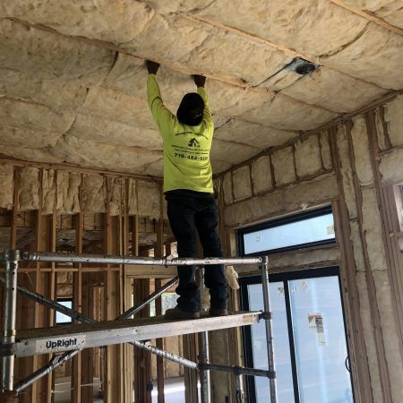 Man Installing Fiberglass Insulation — Colorado Springs, CO — Grand View Construction Man Installing Fiberglass Insulation — Colorado Springs, CO — Grand View Construction