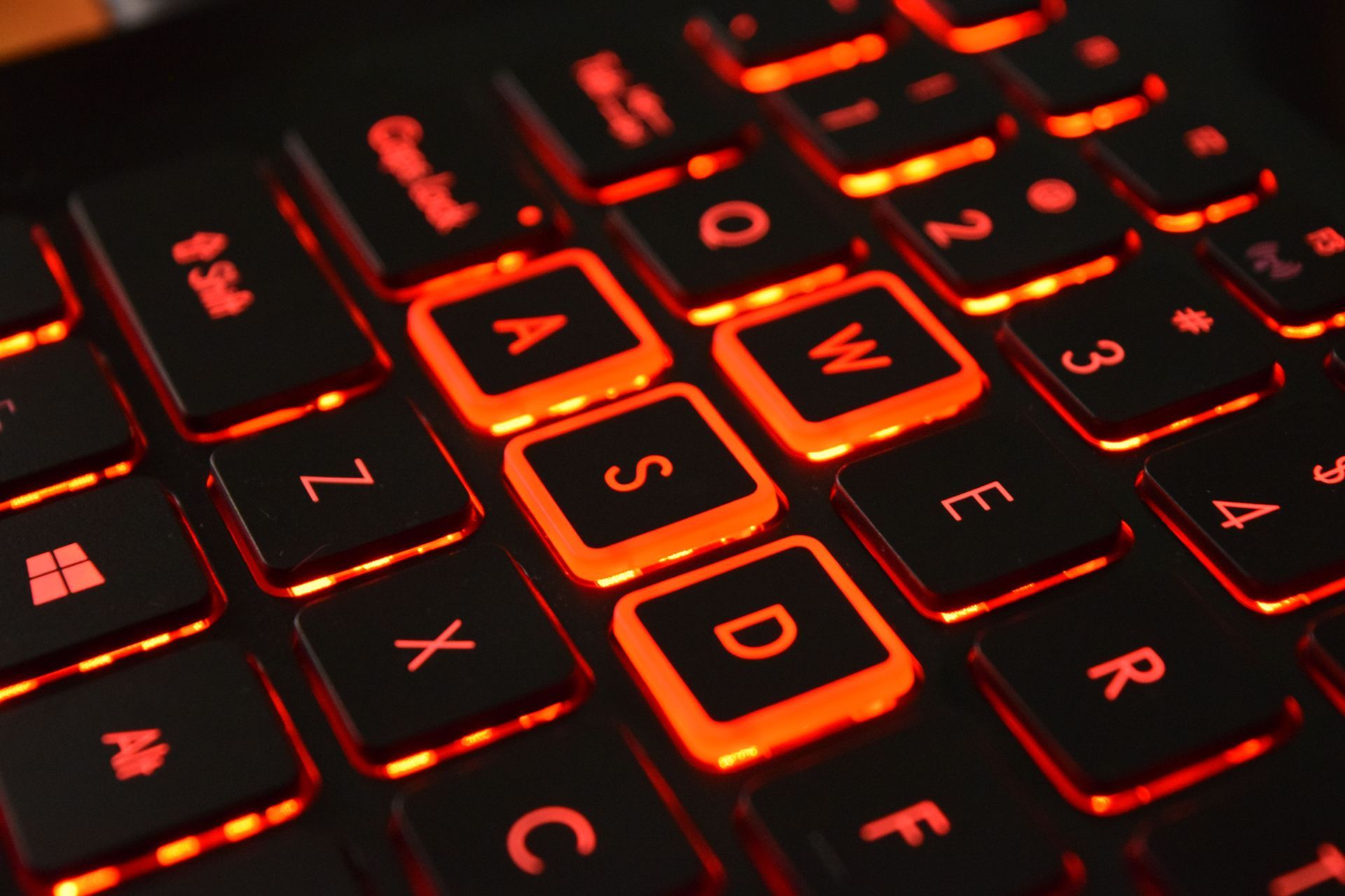 Close-up of a red backlit keyboard with the WASD keys highlighted in orange