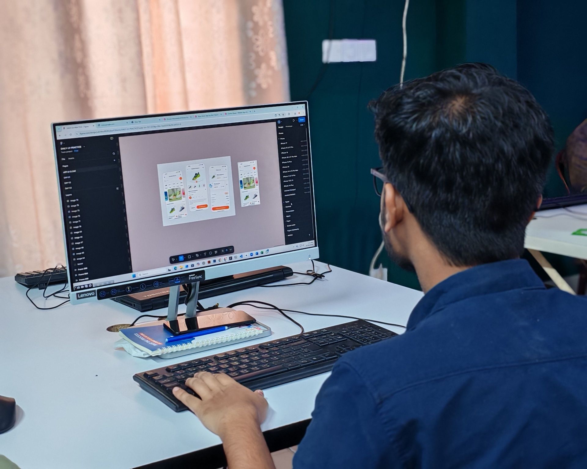 Person working at a desk on a desktop computer with design software open on the screen.