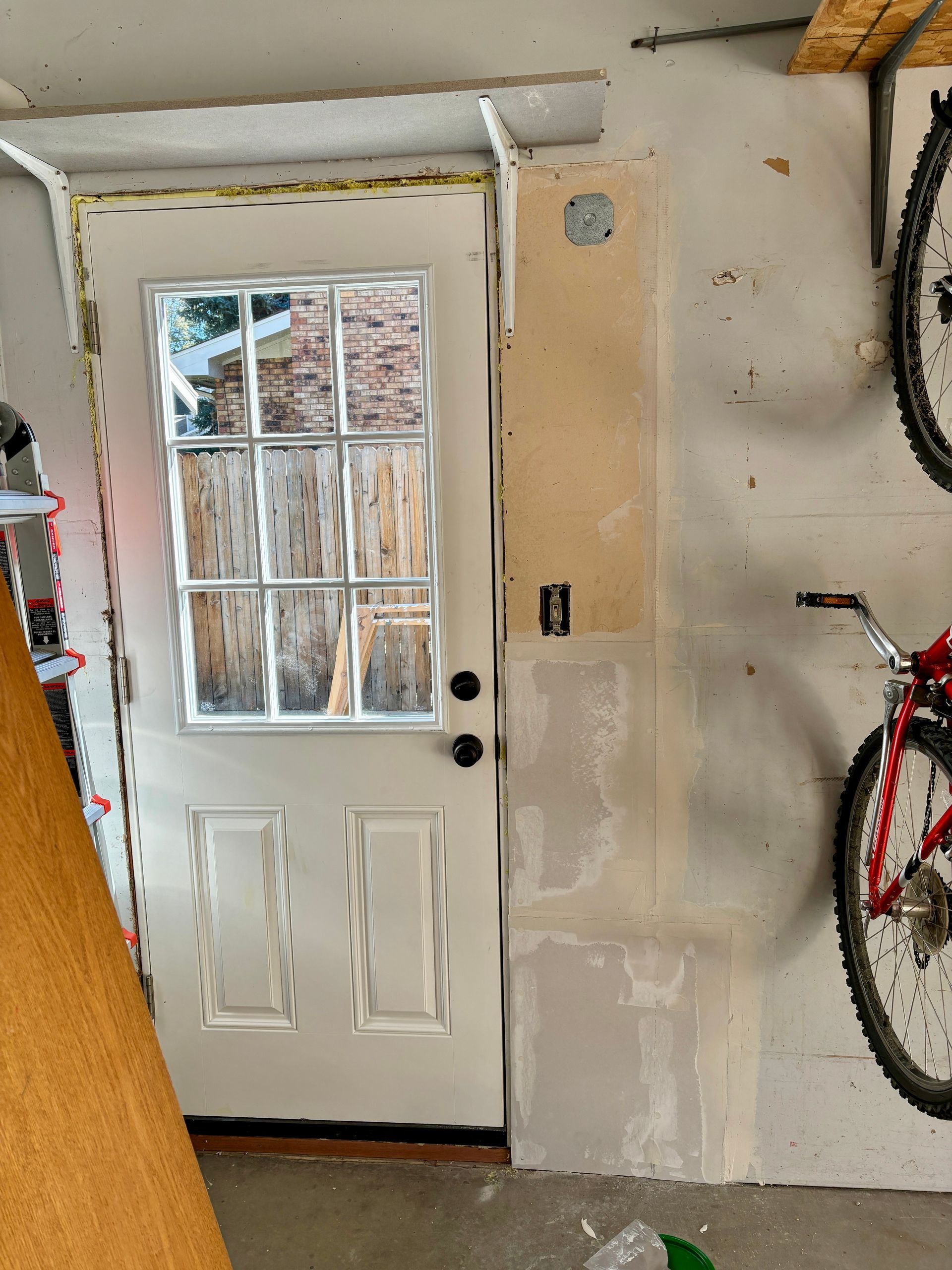 White door with glass panes in a garage. A bicycle hangs on the wall.