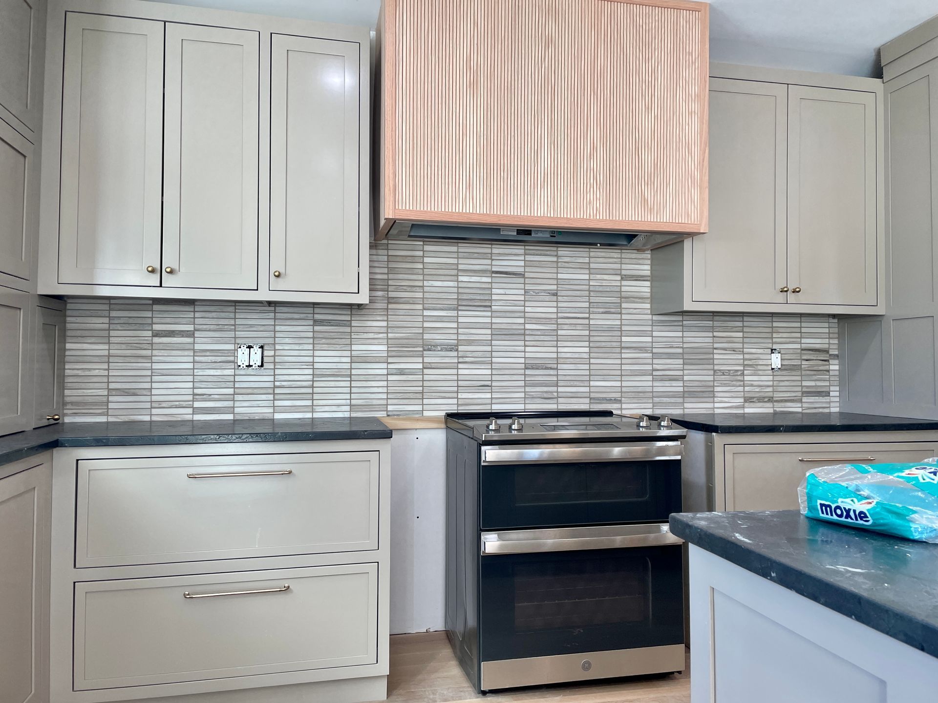Kitchen with gray cabinets, a stainless steel oven, and light gray tile backsplash.