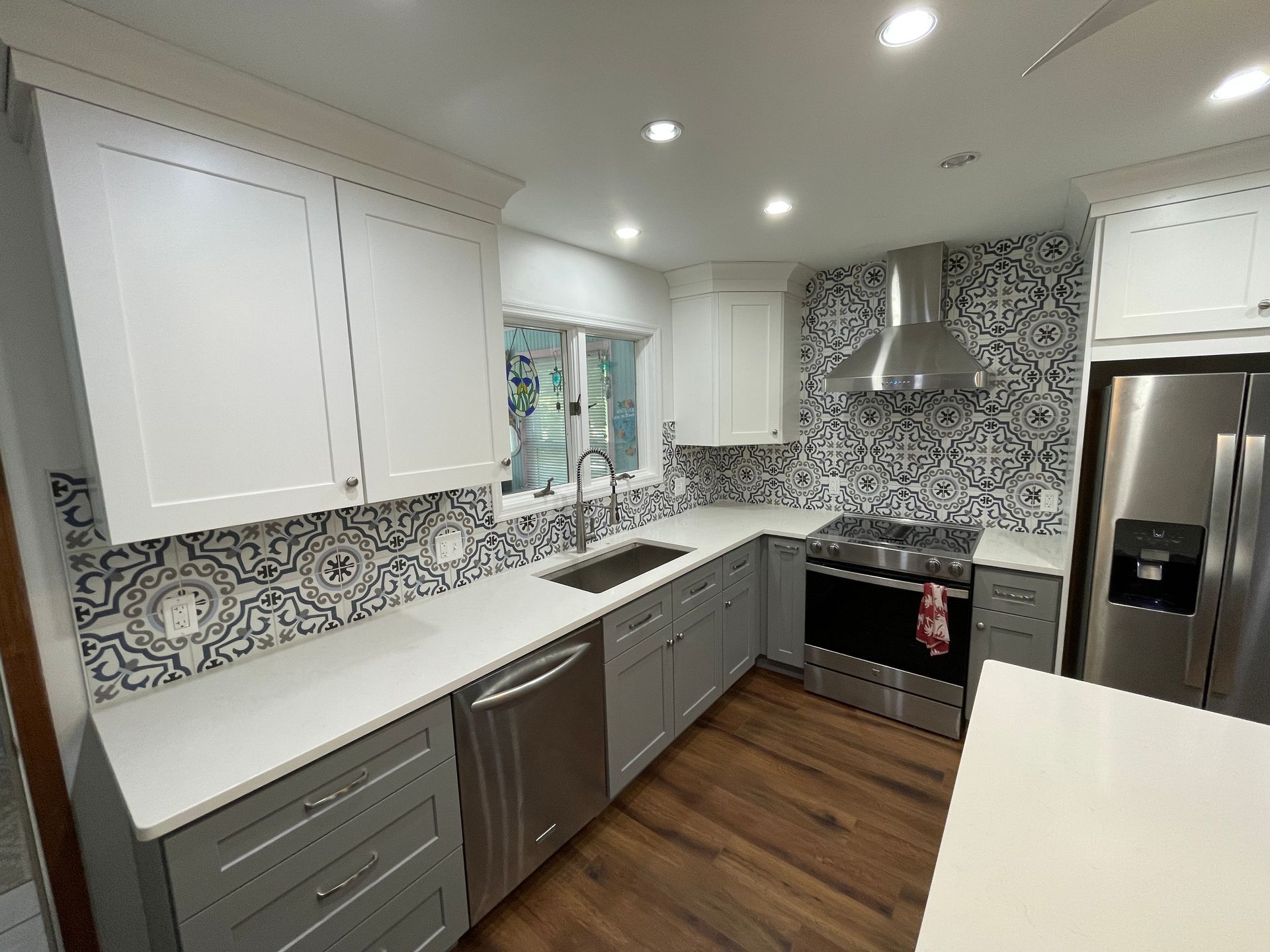 Modern kitchen with white and gray cabinets, stainless steel appliances, and patterned backsplash.