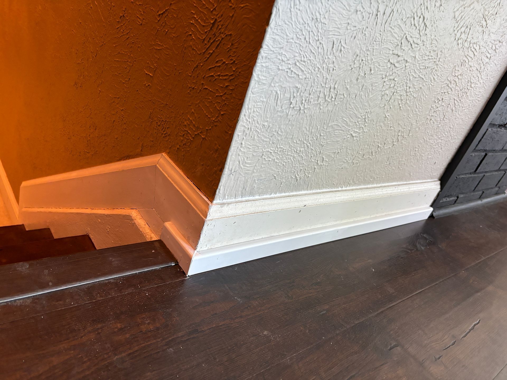 White baseboard along textured walls, dark wood floor.