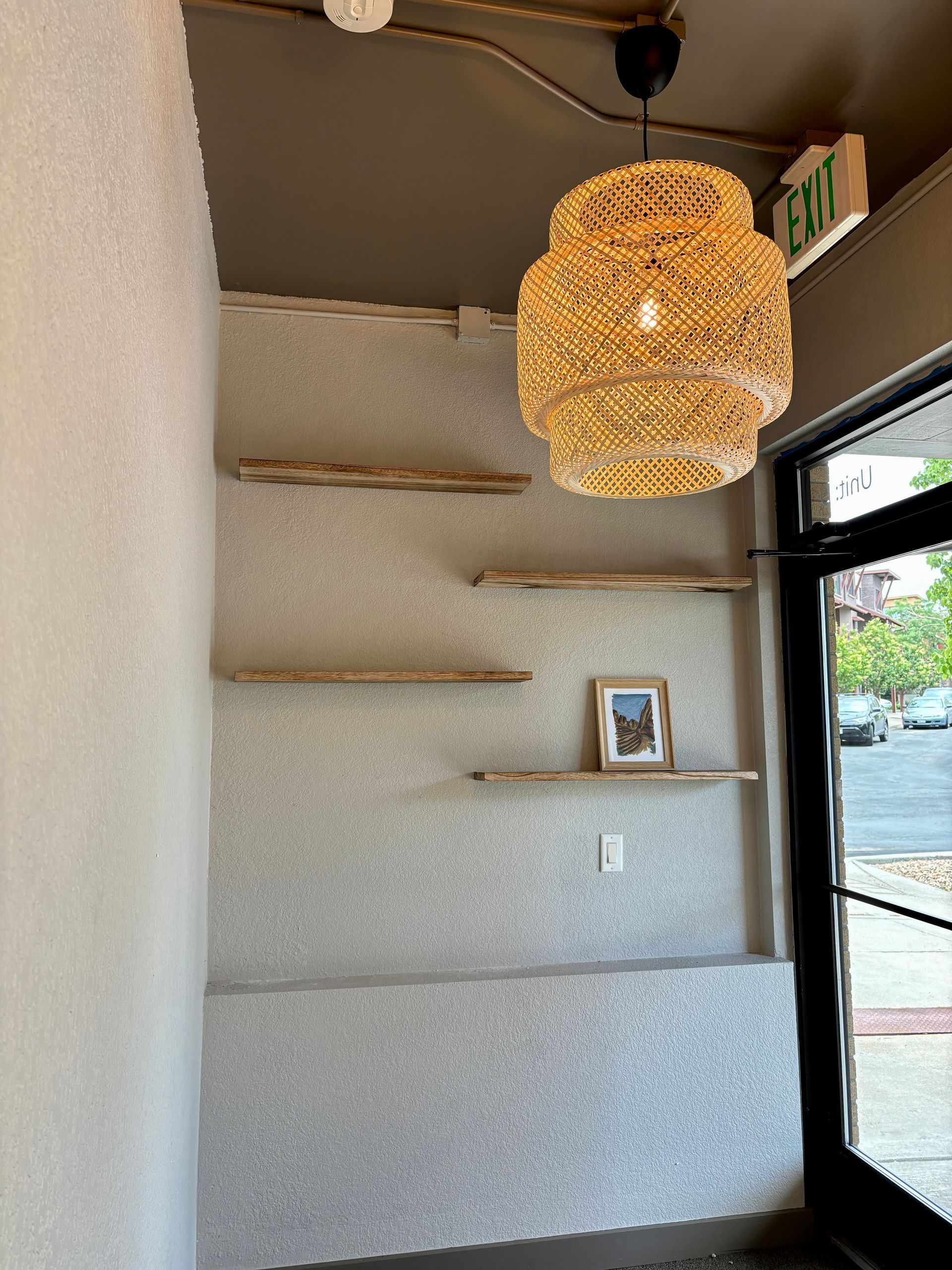 Shelves with decor on textured wall, lit by a decorative pendant lamp near an entryway.