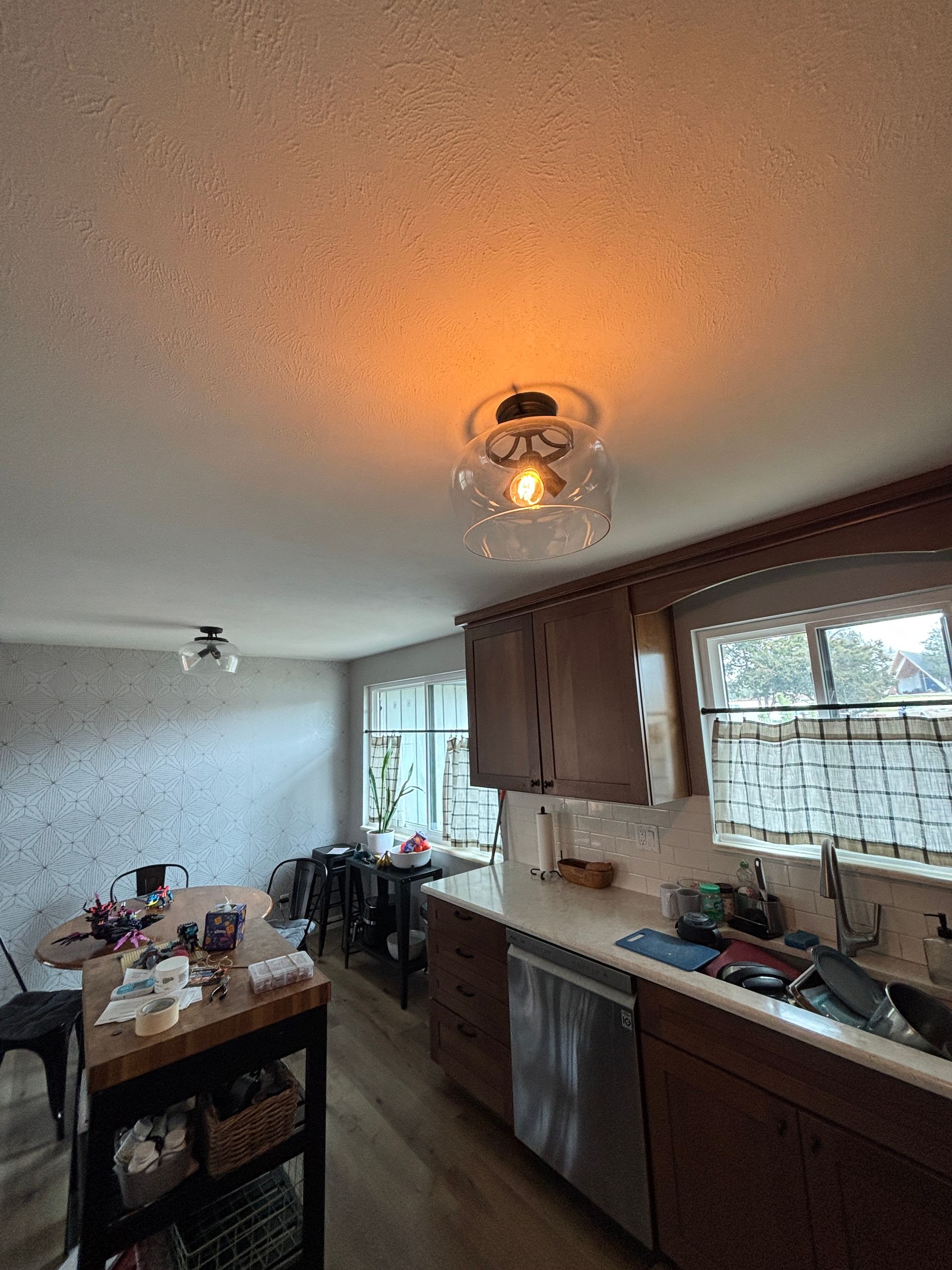 Kitchen with a ceiling light, wooden cabinets, and an island with items on it.