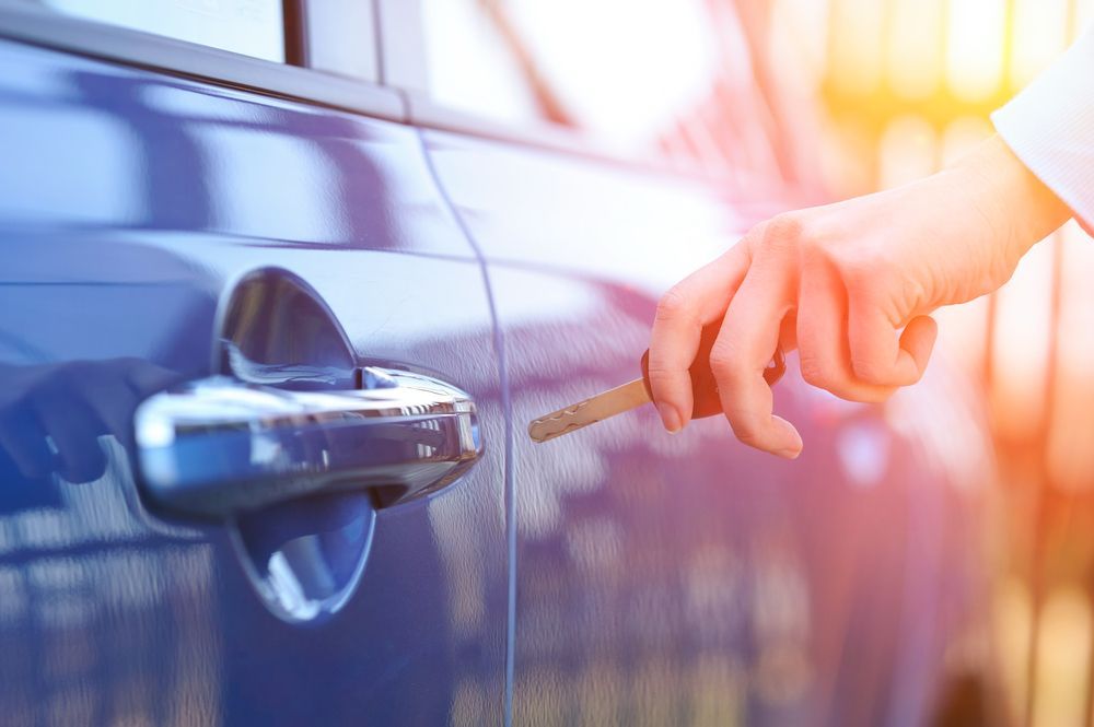 Hand Unlocking a Blue Car Door With a Key. Sunlight Shines on the Scene — Lady Locksmith in Mackay, QLD