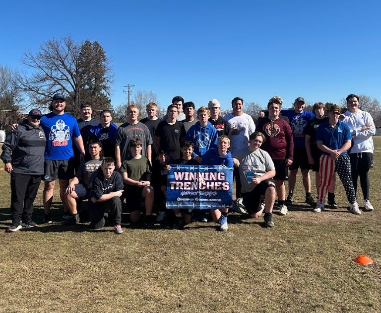 A group of people standing on a field outdoors, holding a sign that says 
