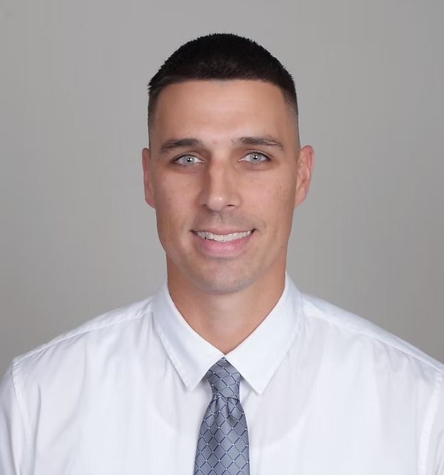 A man in a white shirt and tie smiles for the camera