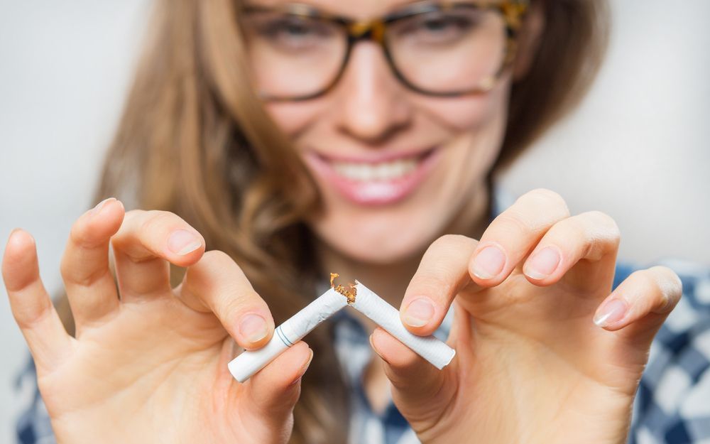 Woman breaking cigarette in half following a stop smoking hypnotherapy session in Yulee, FL